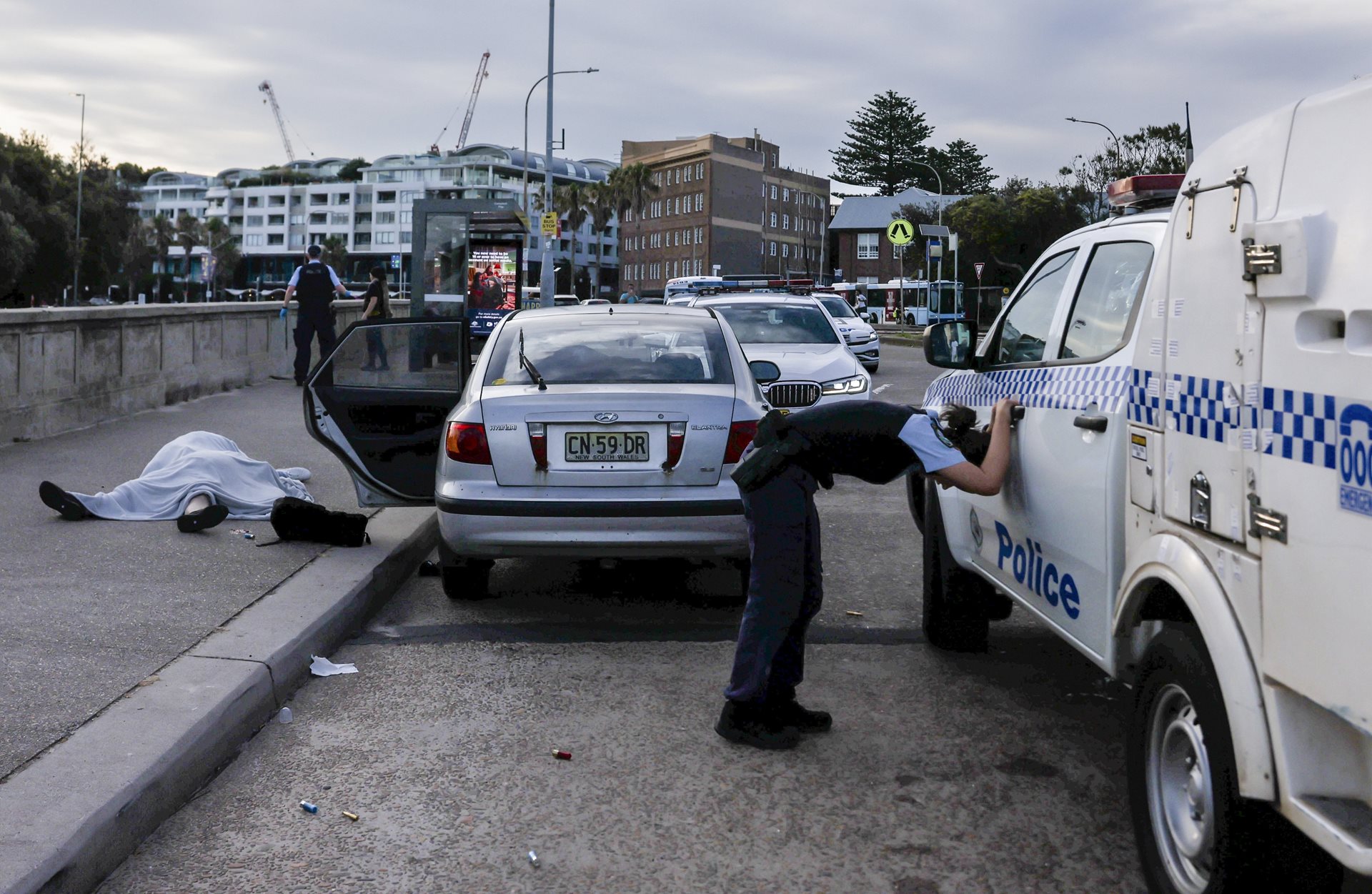 An overwhelmed police officer leans over near the bodies of Boris and Sofia Gurman. The Gurmans, who were just weeks away from their 35th wedding anniversary, were killed during the Bondi Beach Terror Attack in Sydney, Australia while attempting to disarm one of the shooters.