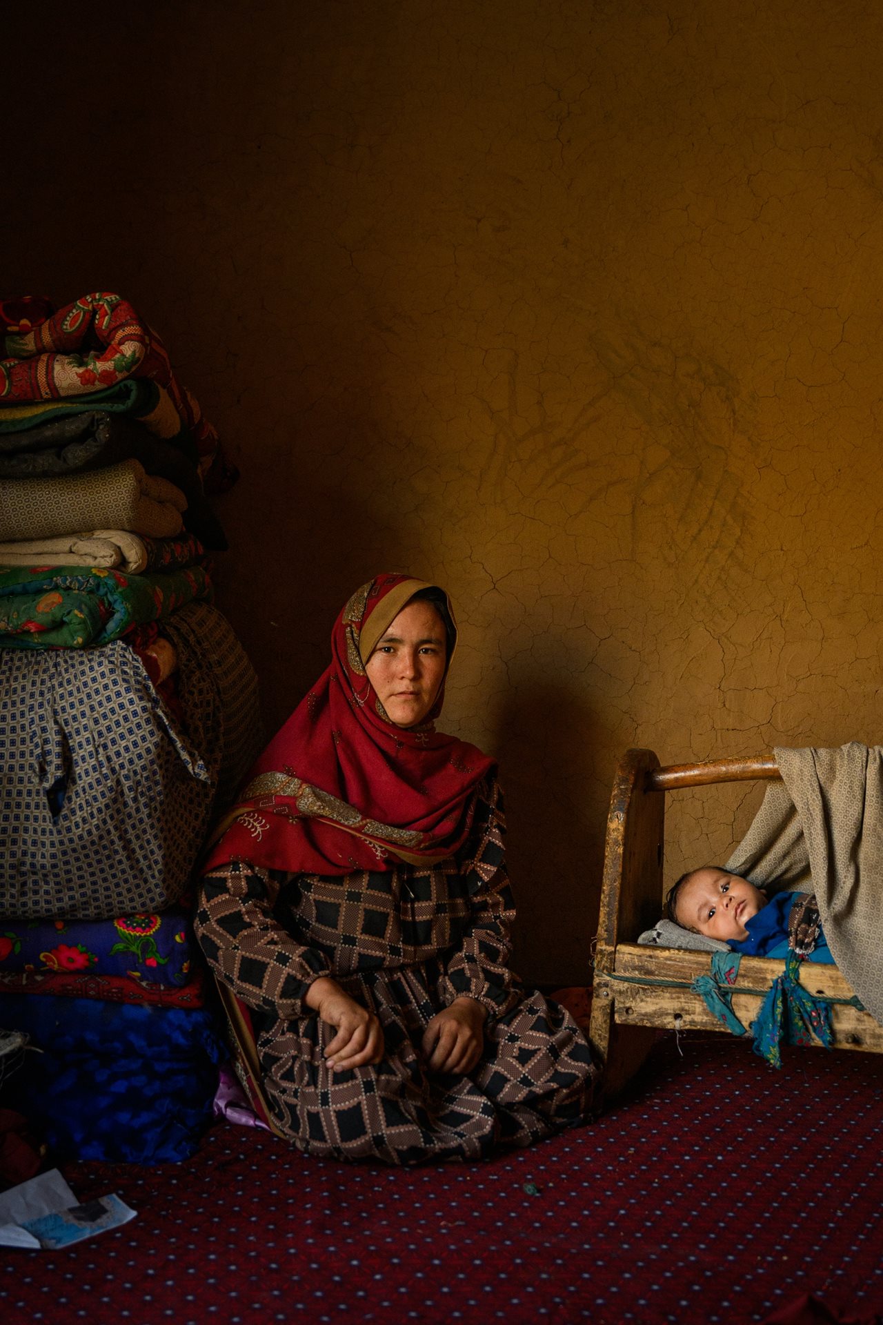 Mariam sits with her child Reza, born at home four months previously. Reza is her third child delivered at home, as a clinic has always been too far to get to. The previous year, her five month old daughter died of pneumonia while the family tried to reach care. Samchag, Miramor district, Daikundi province, Afghanistan.